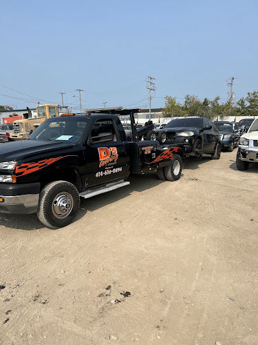 A D's Towing & Recovery black flame-striped tow truck parked in the yard with vehicles behind it.